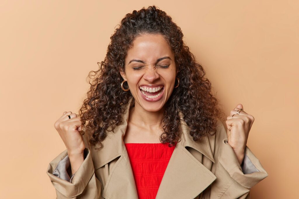 Overjoyed Brazilian woman clenches her fists tightly showcasing her strength and resilience ready to