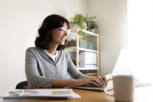 Caucasian woman working at home office. Happy female entrepreneur using laptop.